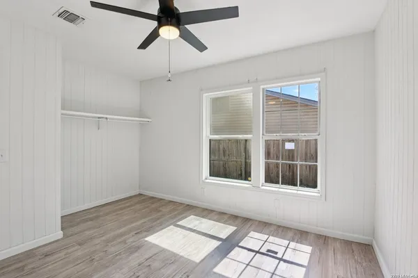a view of empty room with wooden floor and fan