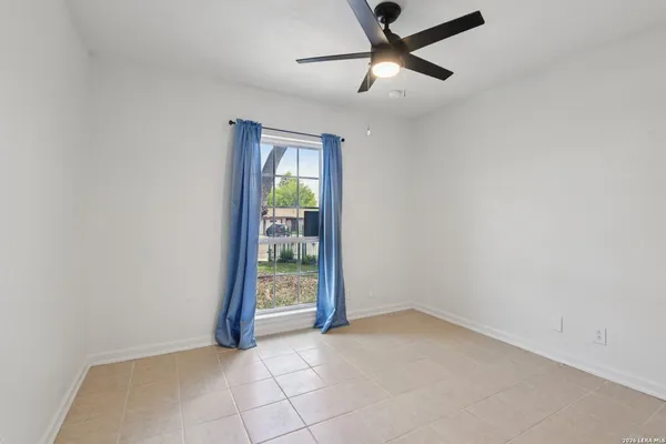 an empty room with ceiling fan and window