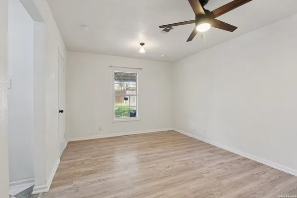an empty room with wooden floor fan and windows