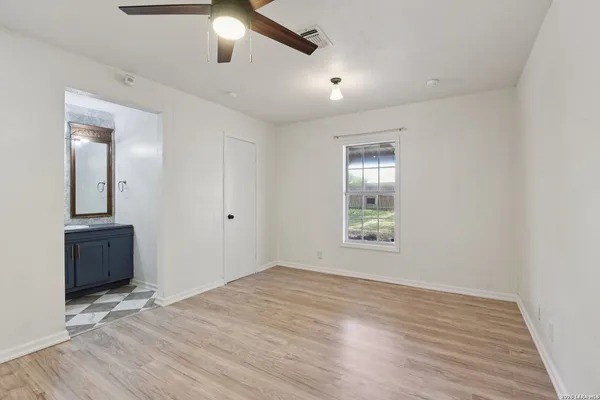 a view of an empty room with window and wooden floor