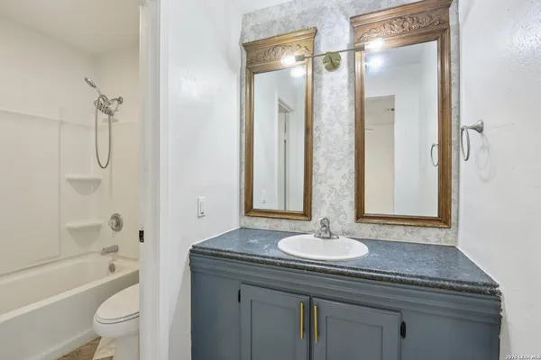 a bathroom with a granite countertop sink a toilet a mirror and shower