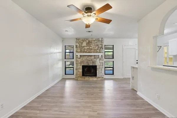 a view of a livingroom with a fireplace a chandelier fan and wooden floor