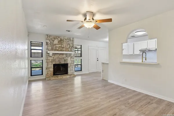 an empty room with wooden floor fireplace and windows
