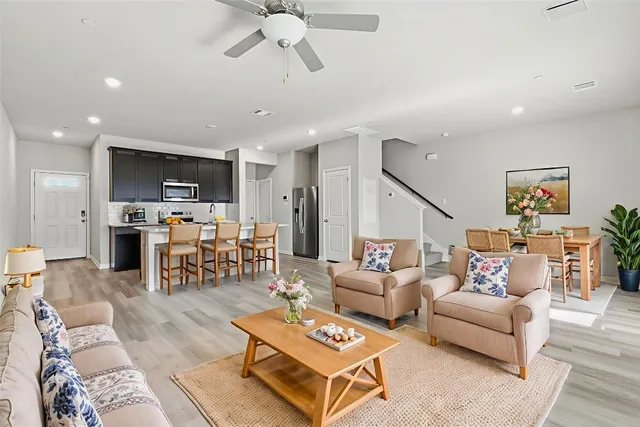 a living room with furniture kitchen view and a wooden floor