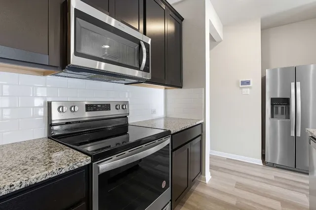a kitchen with stainless steel appliances granite countertop a refrigerator and a stove top oven