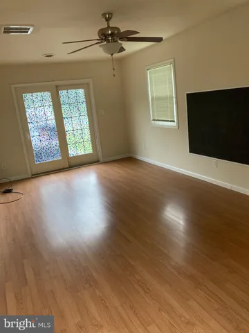 an empty room with wooden floor fan and windows