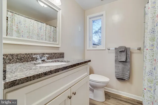 a bathroom with a granite countertop toilet a sink and a mirror