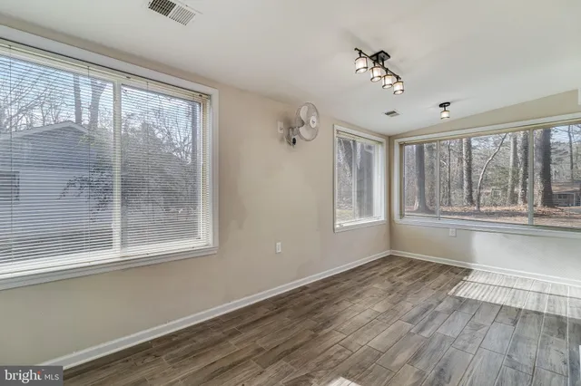 a view of an empty room with a window and wooden floor