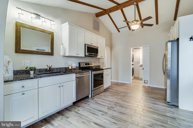 a kitchen with granite countertop a sink cabinets and stainless steel appliances