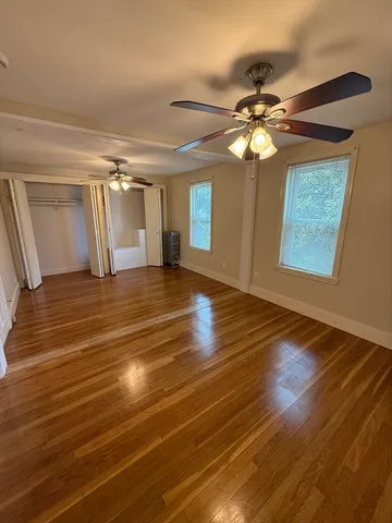 a view of empty room with wooden floor and fan