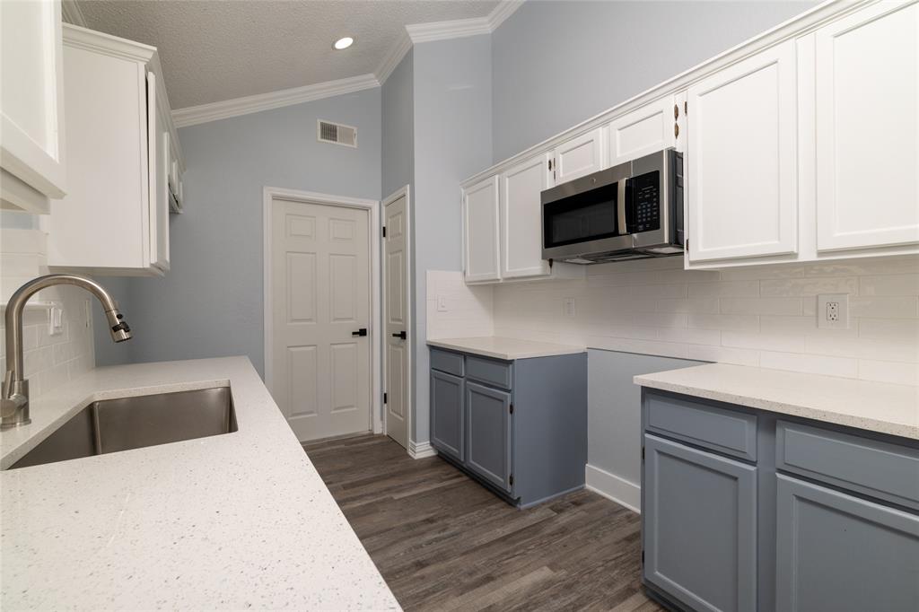 2513 Poplar Spring Road Fort Worth, TX 76123 - Photo 21 of 40 Kitchen featuring vaulted ceilings, wood-finish flooring, white subway tile backsplash, white countertops, and stainless steel appliances