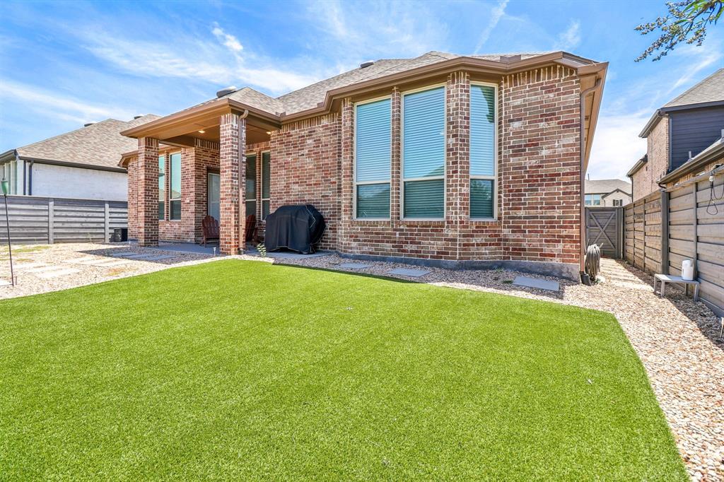 847 Longbranch Way Little Elm, TX 76227 - Photo 30 of 39 Back of property with a fenced backyard, brick siding, a patio, and a shingled roof