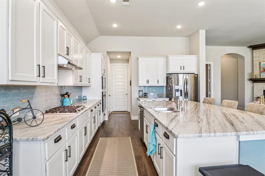 847 Longbranch Way Little Elm, TX 76227 - Photo 10 of 39 Kitchen with a large island, white cabinetry, arched walkways, dark wood-type flooring, and stainless steel appliances