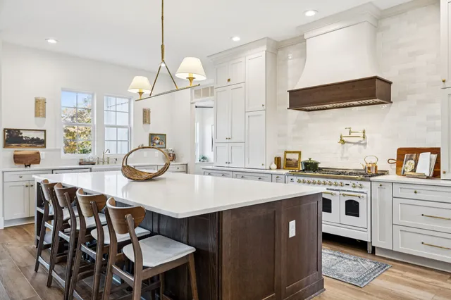 a large kitchen with stainless steel appliances granite countertop a stove and a wooden floor