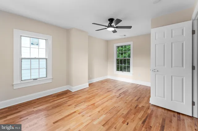 a view of empty room with wooden floor and fan