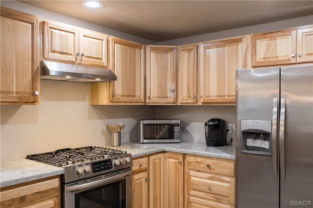 270 Spruce Lane Sugarloaf, CA 92386 - Photo 18 of 39 a kitchen with stainless steel appliances granite countertop a stove a refrigerator and a sink with wooden cabinets