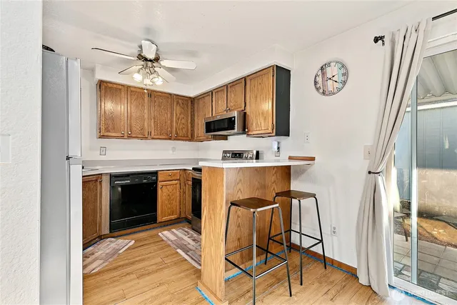 a kitchen with stainless steel appliances granite countertop a stove top oven a refrigerator a sink and a stove with wooden floor