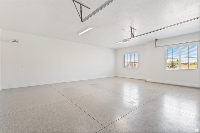 1192 East Corral Way Washington, UT 84780 - Photo 67 of 81 Spacious garage featuring a durable concrete floor, two windows with horizontal blinds, and overhead fluorescent lighting fixtures