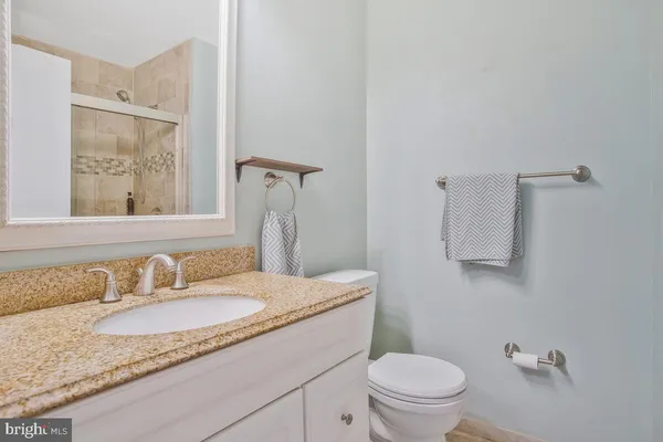 a bathroom with a granite countertop sink mirror vanity and toilet