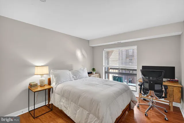 a bedroom with a bed a desk and chair with window