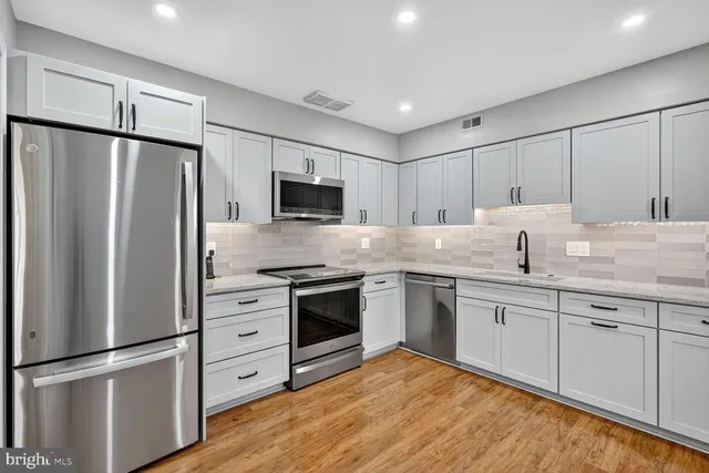 a kitchen with granite countertop a refrigerator stove and sink