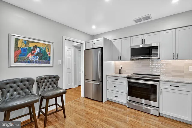 a kitchen with stainless steel appliances a stove a refrigerator and a fireplace