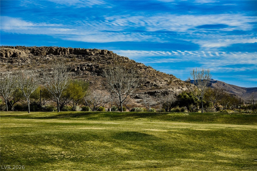 9916 Sable Point Street Las Vegas, NV 89178 - Photo 62 of 73 Green fairways stretch towards a rugged mountain backdrop under a wide blue sky.
