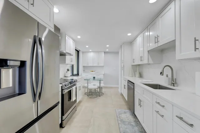 a kitchen with stainless steel appliances sink a refrigerator and white cabinets