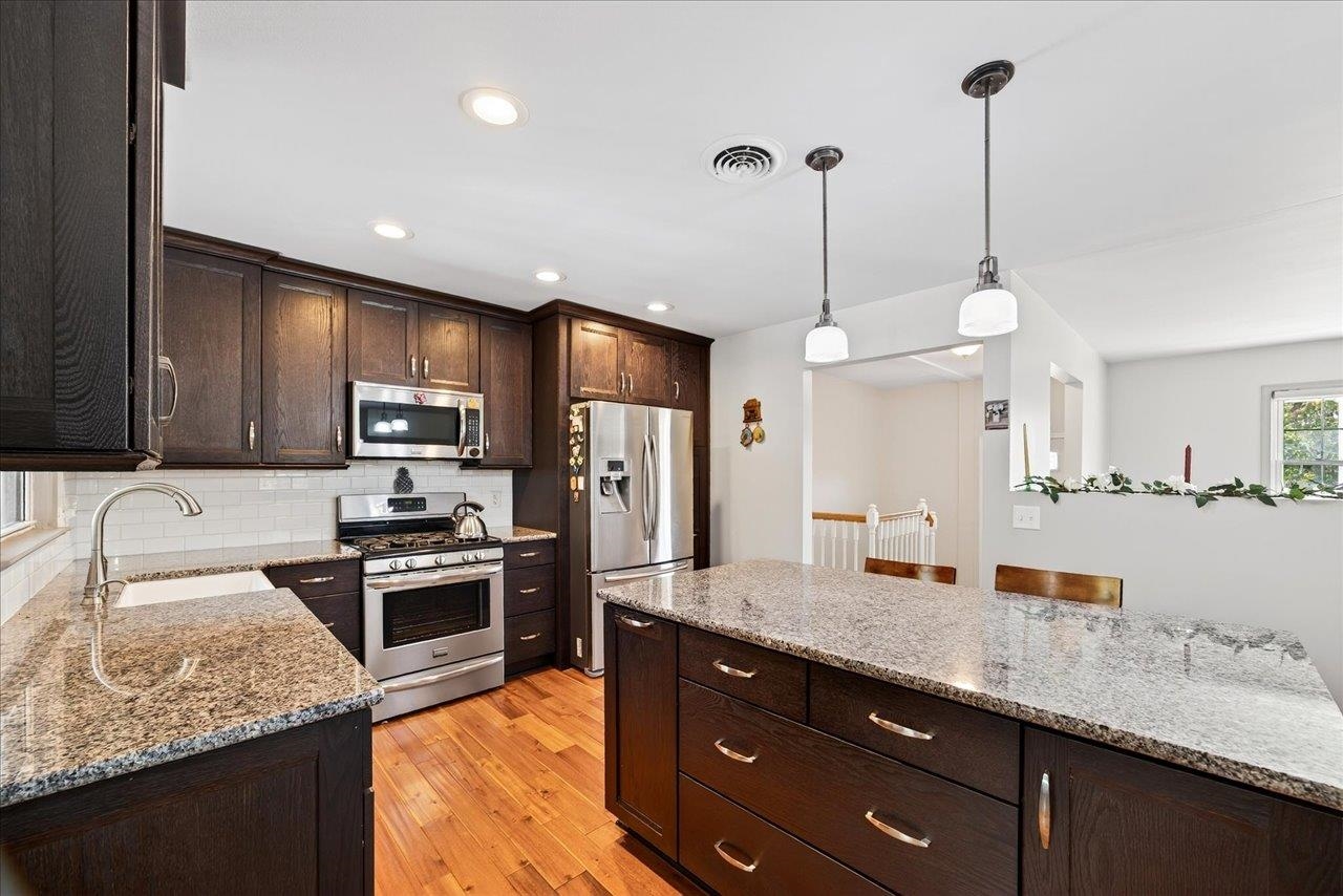 a kitchen with stainless steel appliances granite countertop sink stove refrigerator and cabinets