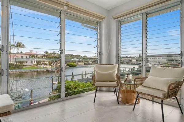a living room with patio furniture and floor to ceiling window