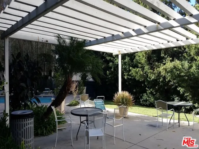 a view of patio with table and chairs under an umbrella with a small yard