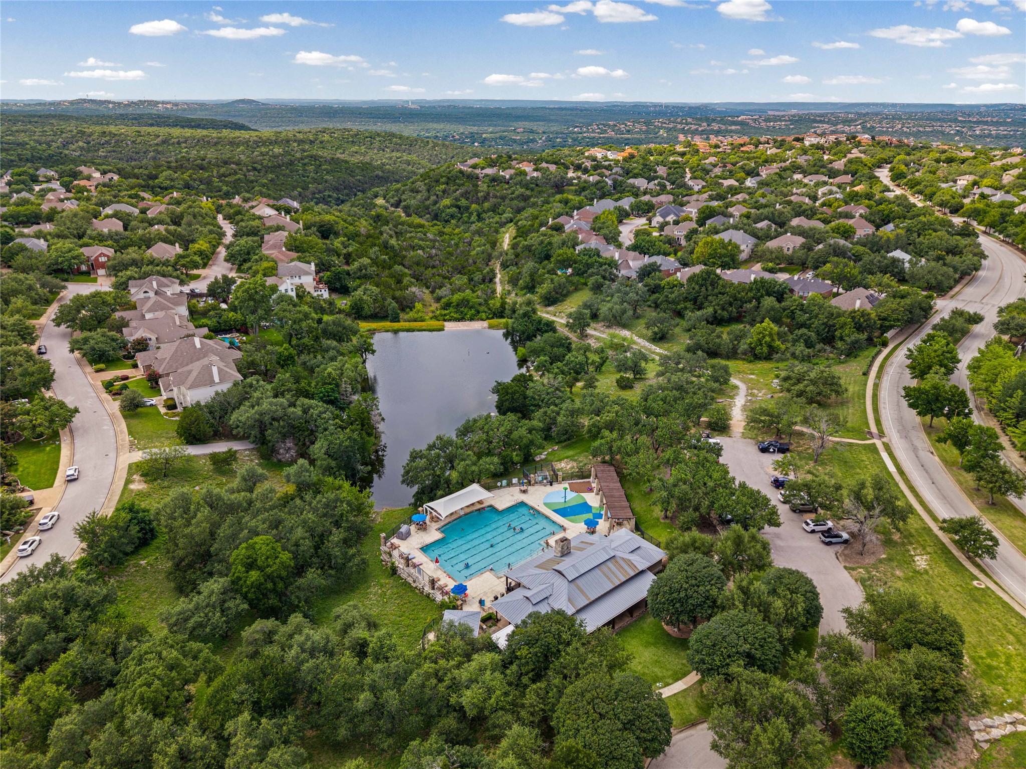 10700 Pointe View Drive Austin, TX 78738 - Photo 34 of 35 An aerial panorama reveals a vast, lush community with a sparkling pool, placid lake, and winding roads.