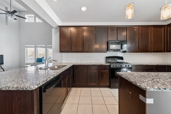 a kitchen with granite countertop stainless steel appliances a sink stove and cabinets