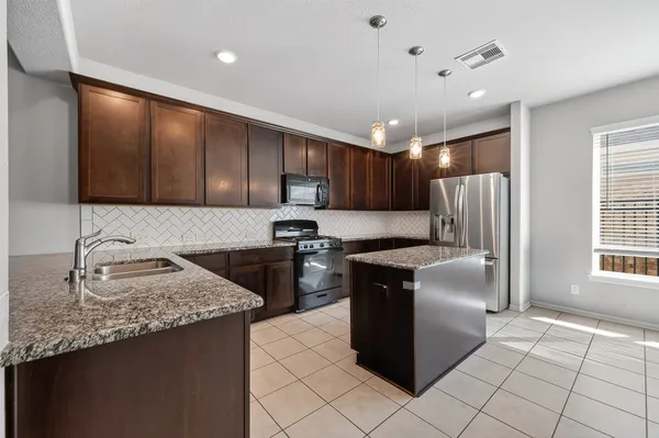 a kitchen with stainless steel appliances granite countertop a refrigerator a sink a stove a microwave and island