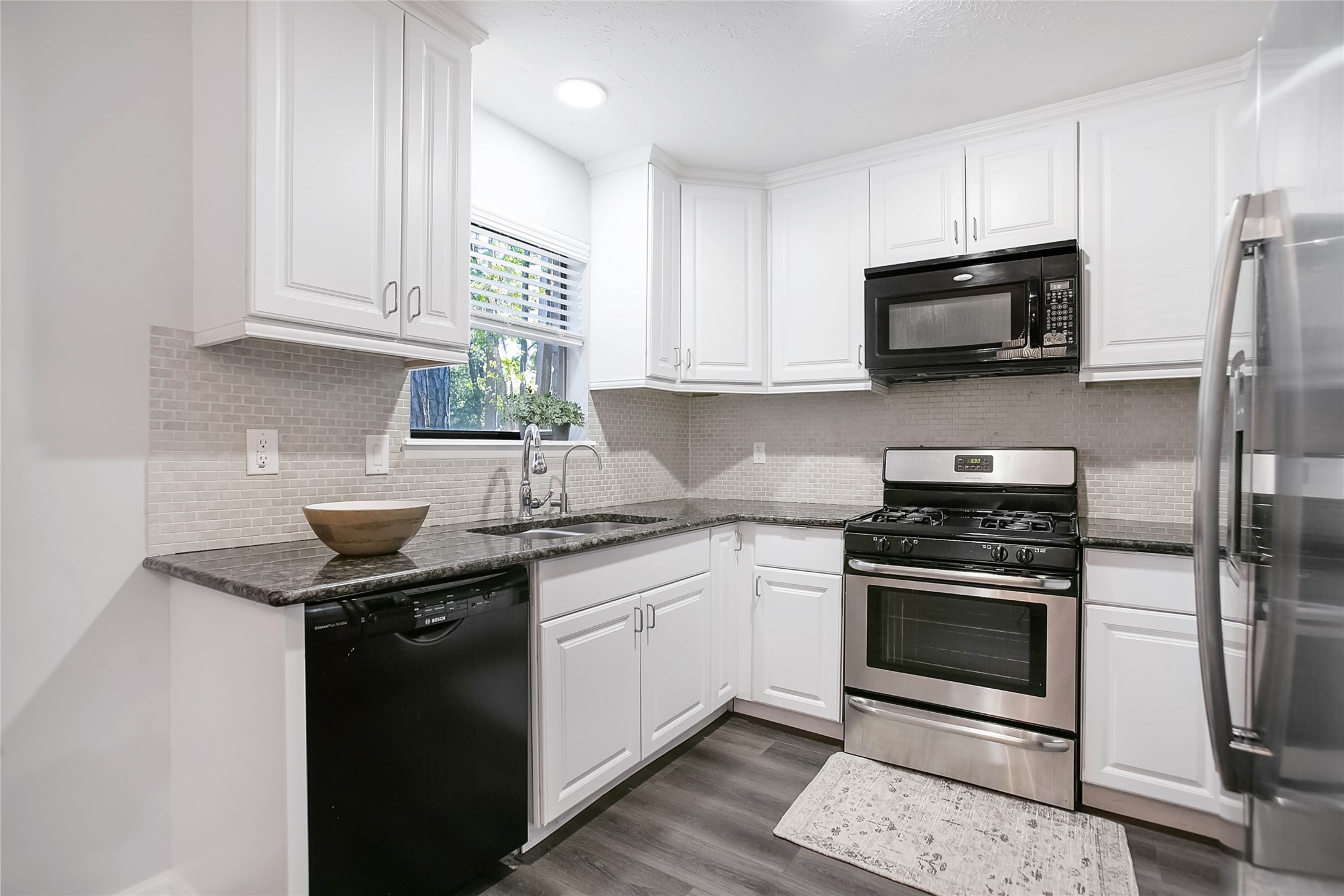 56 East White Willow Circle Spring, TX 77381 - Photo 15 of 45 a kitchen with stainless steel appliances granite countertop a stove a sink dishwasher and a microwave