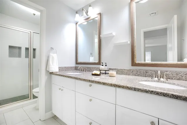 a bathroom with a granite countertop double sink and a mirror