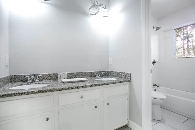 a bathroom with a granite countertop sink mirror vanity and toilet
