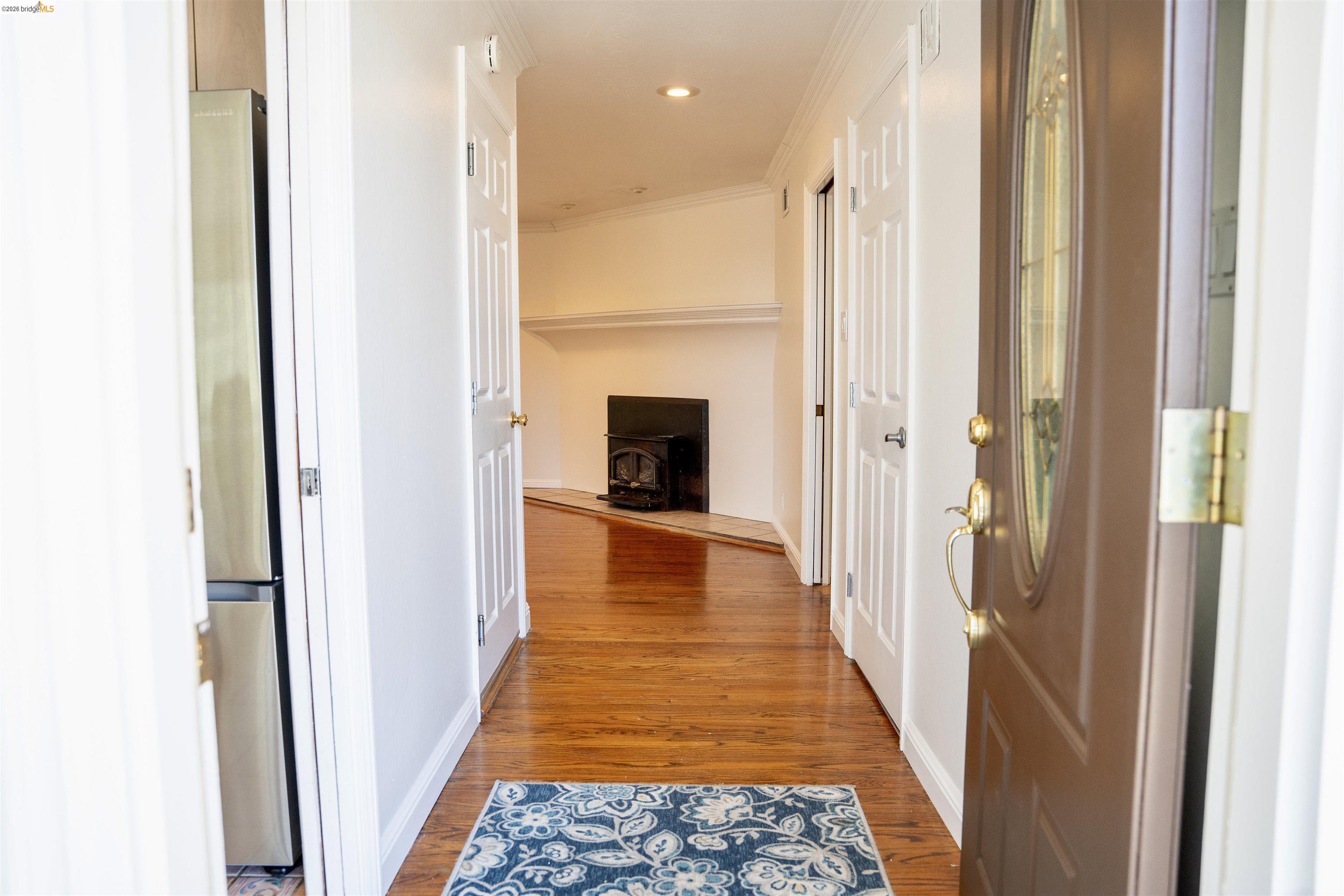 64 Washington Street Novato, CA 94947 - Photo 3 of 21 Entryway featuring a wood-finish floor, an oval lite entry door, white trim, a recessed ceiling light, and a black wood-burning stove