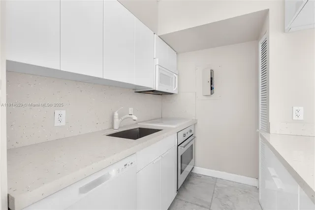 a kitchen with stainless steel appliances granite countertop white cabinets and a sink