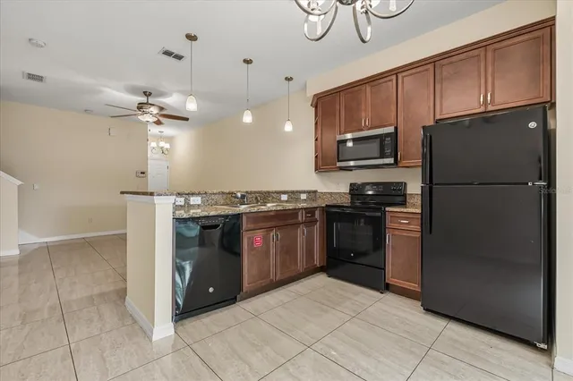 a kitchen with granite countertop a refrigerator and a stove top oven