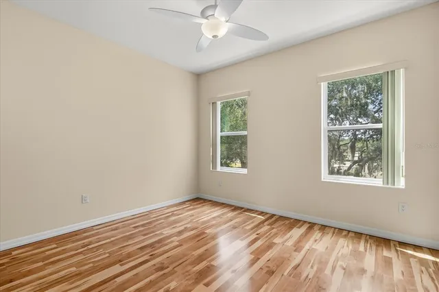 a view of empty room with wooden floor and fan