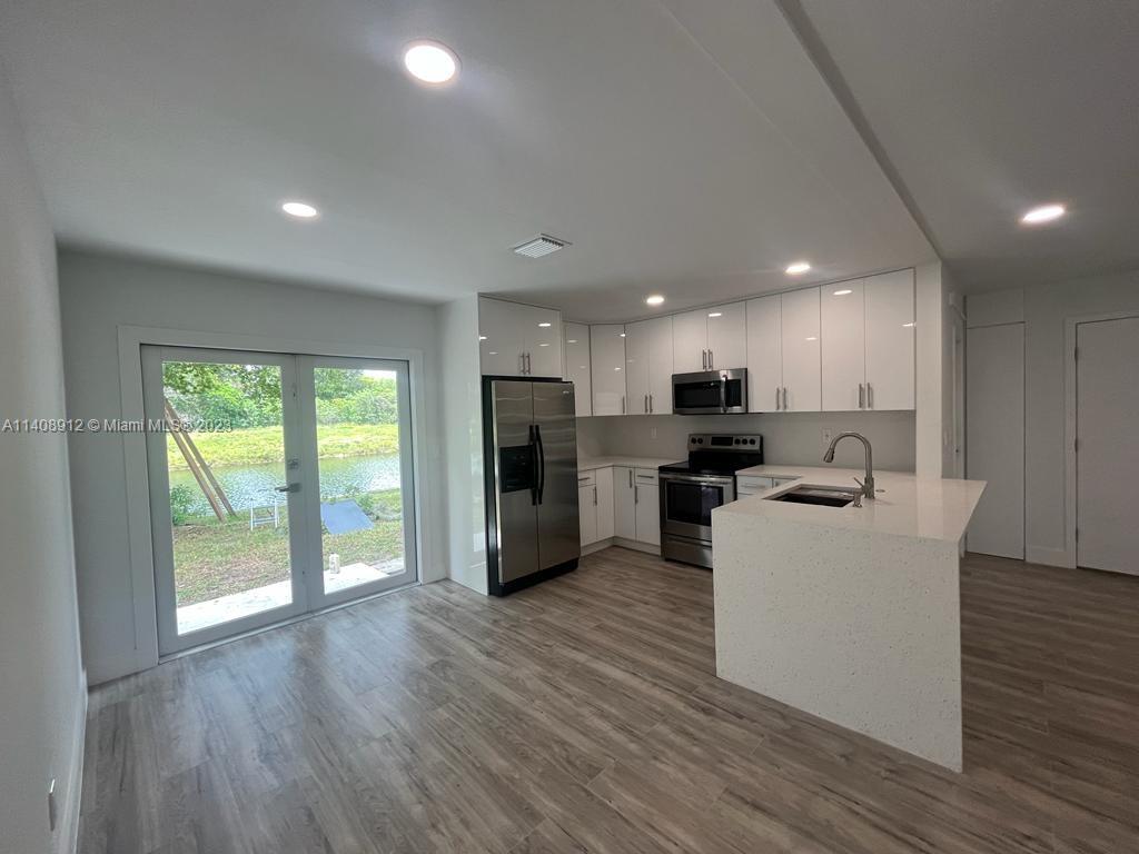 an open kitchen with kitchen island wooden floors and center island