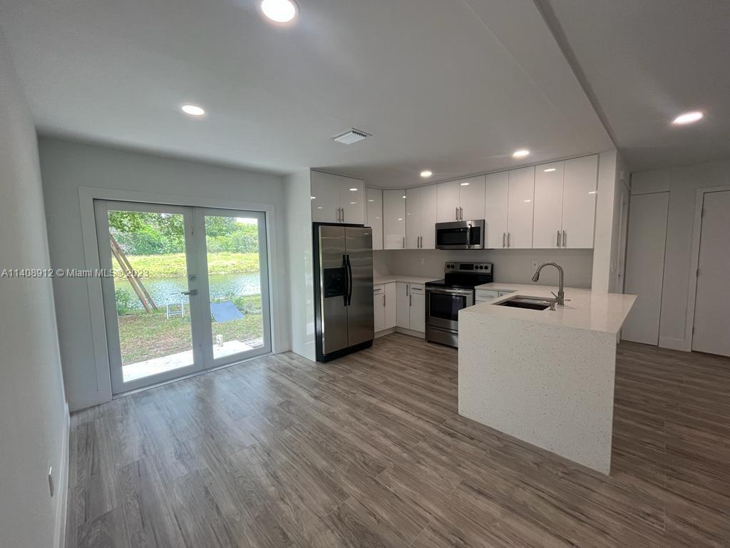 Heathgate Street Tamarac, FL 33321 - Photo 7 of 23 a view of a kitchen with kitchen island wooden floors stainless steel appliances a sink and a window