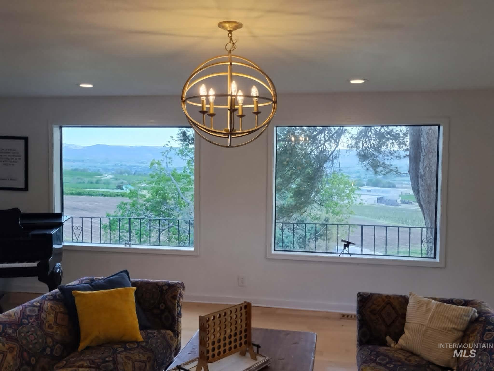 14526 Perfection Lane Caldwell, ID 83607 - Photo 19 of 47 Bright interior space featuring a brass orb chandelier, recessed lighting, and two expansive windows framing distant mountains and agricultural fields