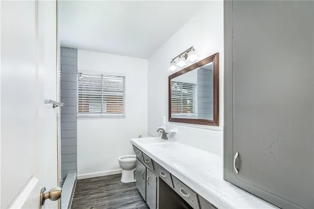 a spacious bathroom with a granite countertop sink a toilet and a window
