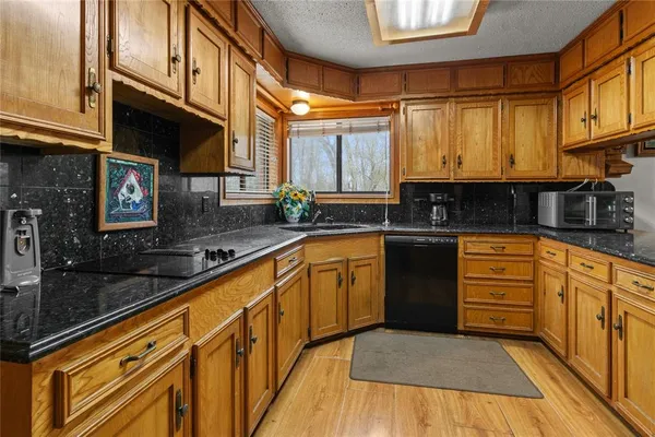 a kitchen with granite countertop a sink a stove cabinets and wooden floor