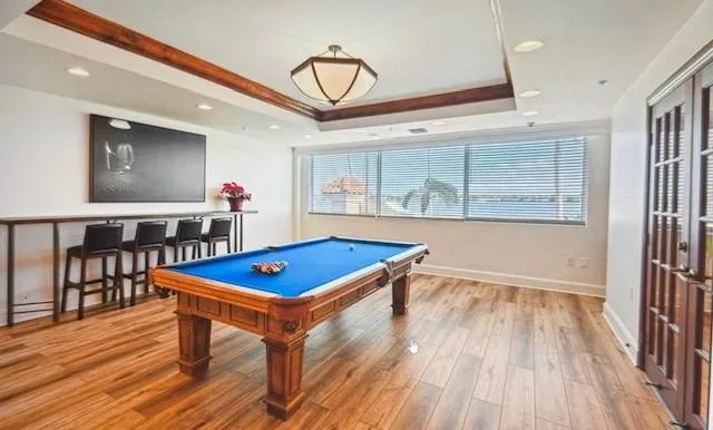 a room with wooden floor pool table and windows