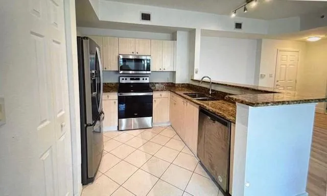 a kitchen with stainless steel appliances granite countertop a stove a sink and a refrigerator