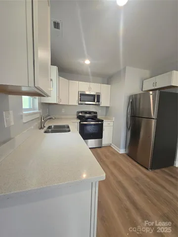 a kitchen with granite countertop a refrigerator and a stove top oven