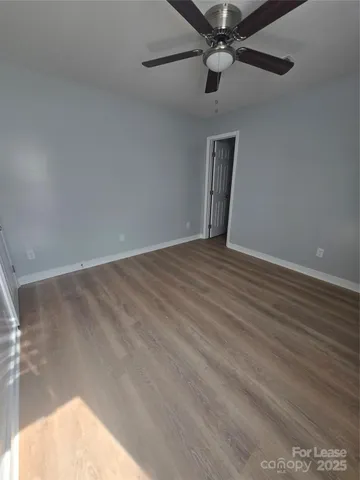en empty room with wooden floor fan and windows
